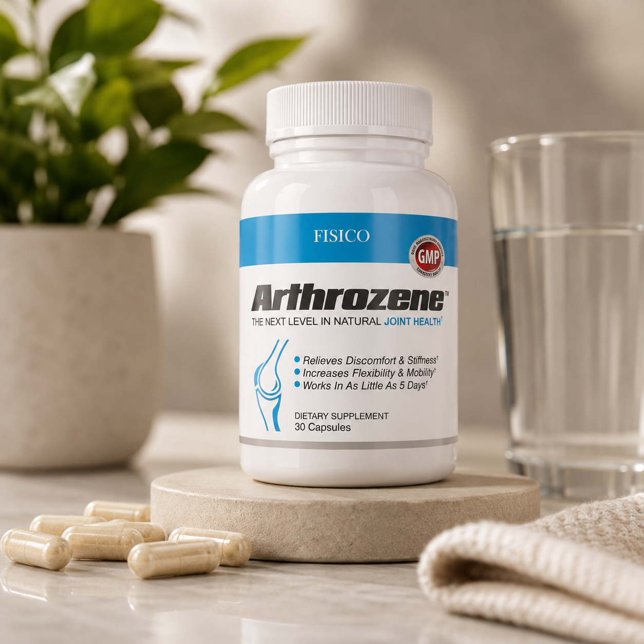 A bottle of FISICO Arthrozene dietary supplement capsules displayed on a stone coaster, with loose capsules scattered nearby, a glass of water, and a potted plant in a bright, clean setting.