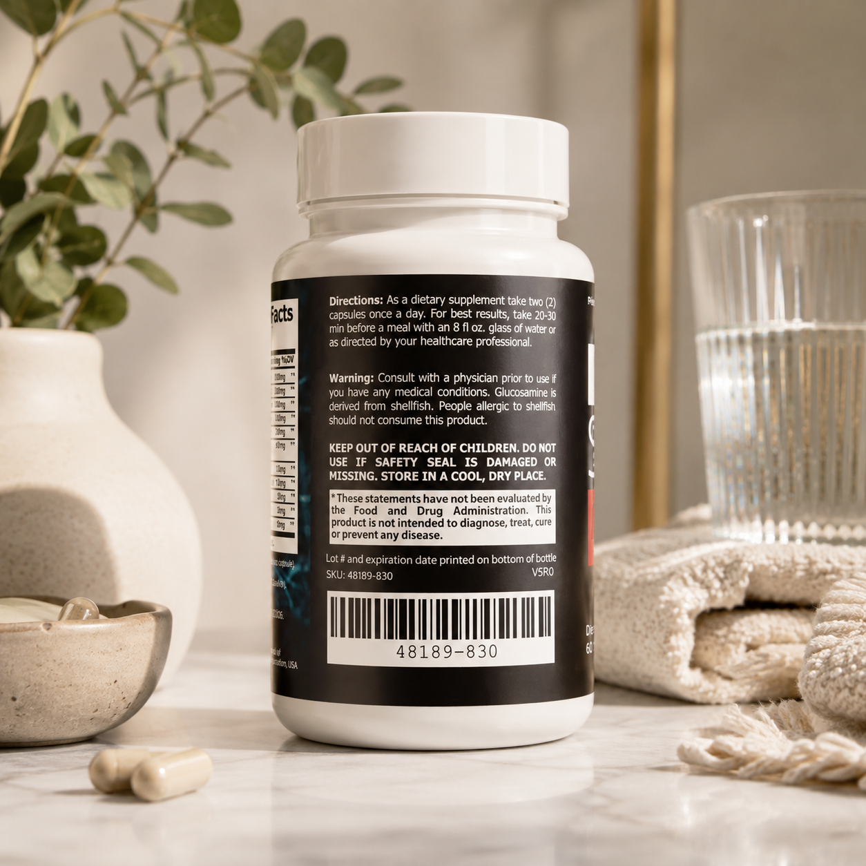 A white supplement bottle with a black label showing directions and warnings, styled on a marble surface with capsules, a glass, and a knit bag in a bright indoor setting.